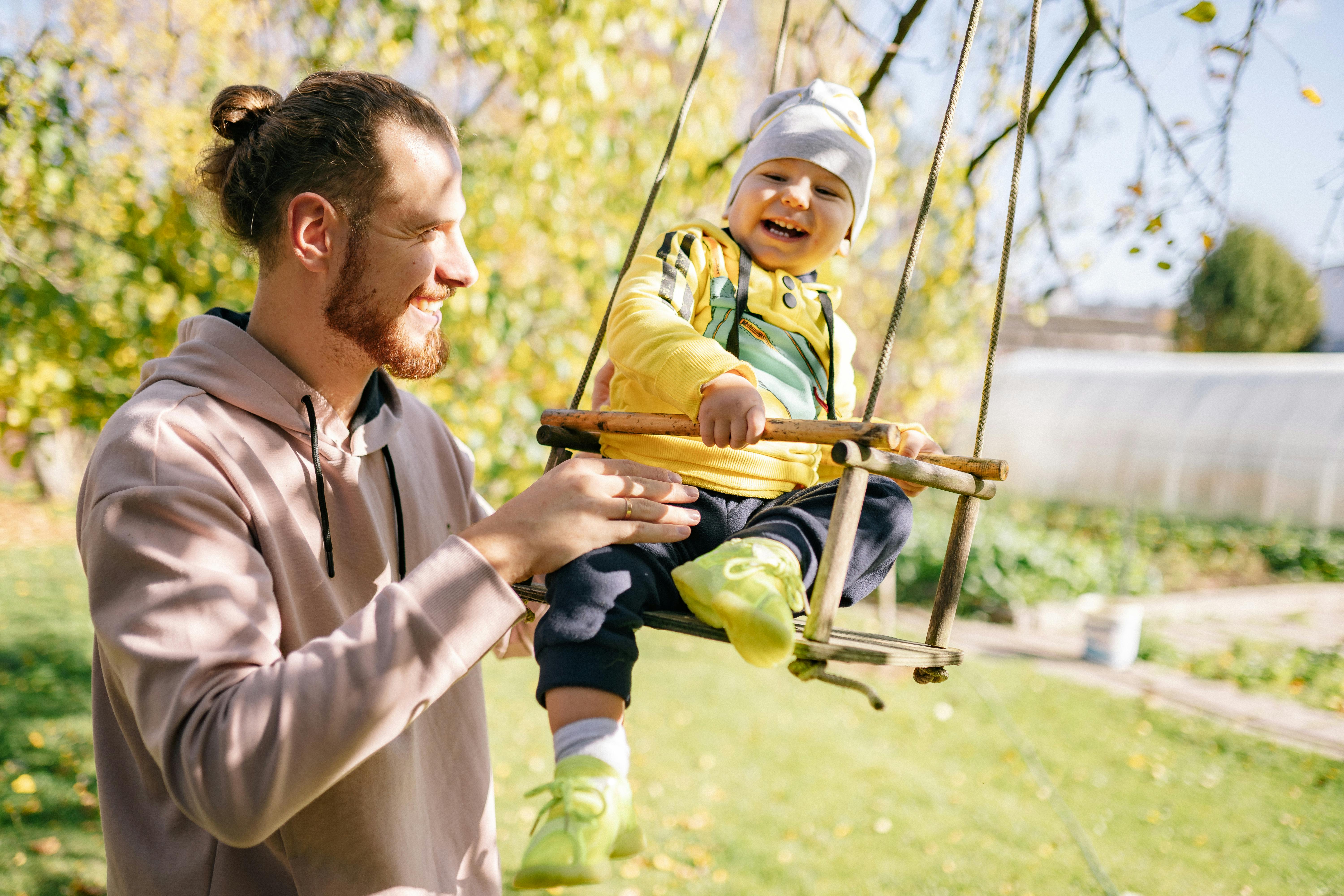 Dad pushing child on swing